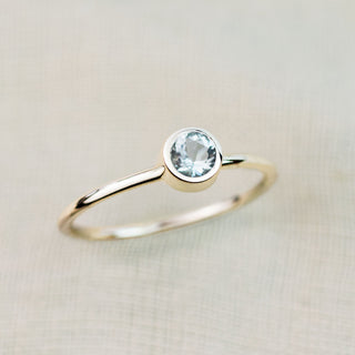 Gold ring with a blue gemstone on a beige background
