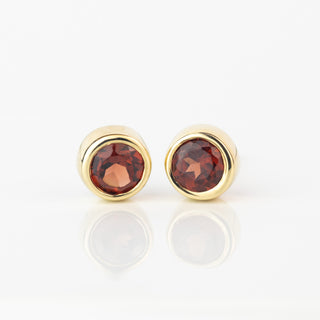 Pair of 9ct gold stud earrings with bezel-set round faceted red garnets
