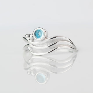 Silver ring with a blue gemstone on a light gray background