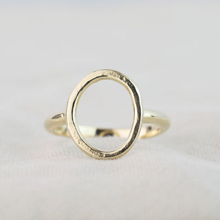 Gold Organic Circle ring resting on linen, showing its circular shape and lightly hammered texture.
