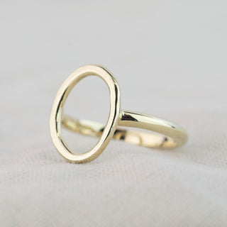 Gold Organic Circle ring resting on linen, showing its circular shape, lightly hammered texture and polished band. 
