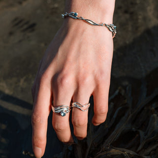 Hand with silver rings and bracelet on a dark background