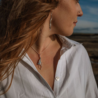 Woman with long hair and a white shirt standing outdoors with a blurred background