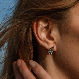 Close-up of an ear with a silver earring against a blurred natural background