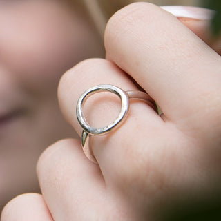 Close-up of a hand wearing a silver ring with a unique design.