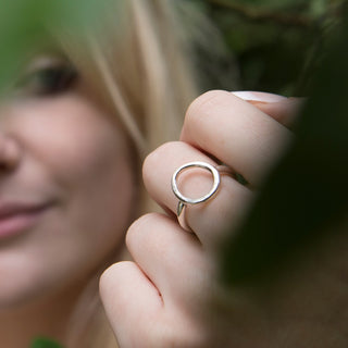 Close-up of a hand wearing a silver ring with a blurred background